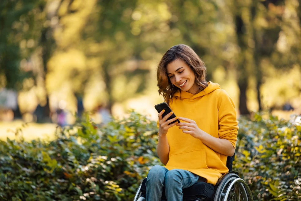 Disabled woman in wheelchair smiling at phone