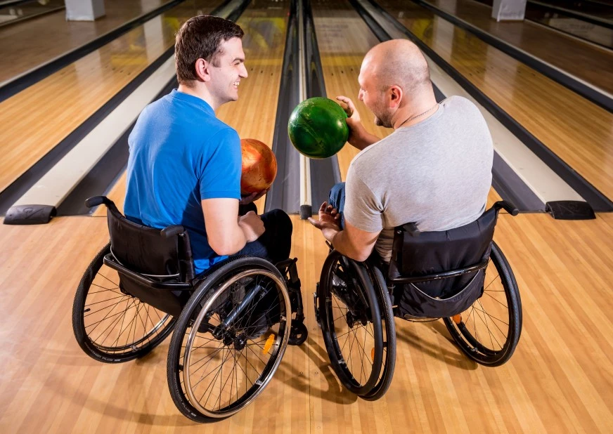Two disabled friends in wheelchairs bowling together
