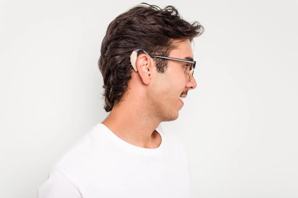 Smiling man wearing hearing aid, image of profile view