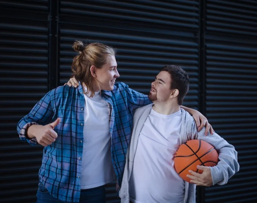 Disabled man with down syndrome holding basketball with carer